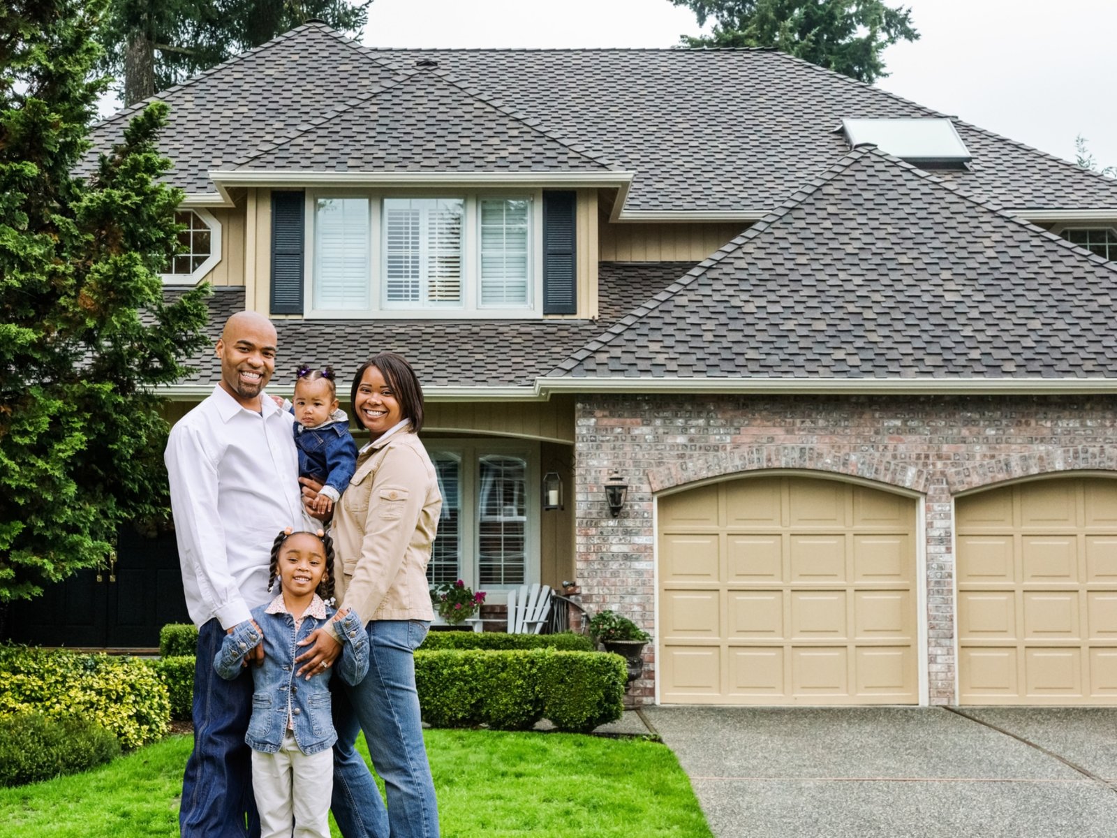 Happy family in front of their home after a Ricketts Construction roofing project